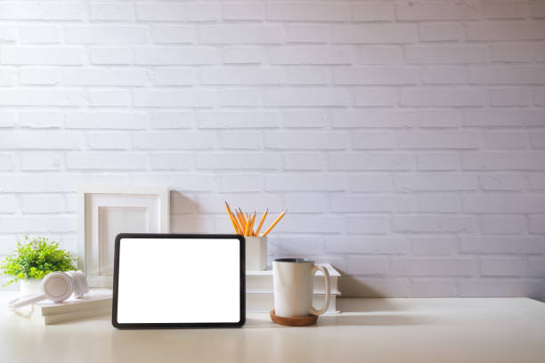 istock Digital tablet with blank display, coffee cup and potted plant on white table. Simple workplace. 1879748204