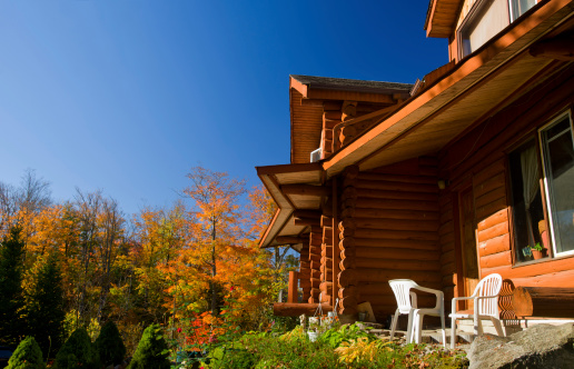 Bright orange leaves hang in front of the top of an old fashioned house in autumn.