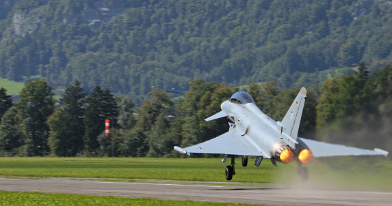 Mollis, Switzerland, August 19, 2023: A German Luftwaffe Eurofighter Typhoon demonstrates an agile takeoff against the lush Swiss landscape at the Mollis airfield.