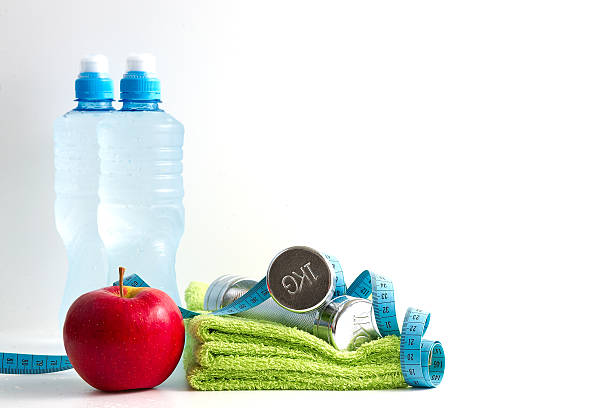 istock Dumbbells with an apple and water on white background. 187976857