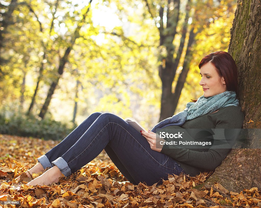 Beautiful pregnant woman sitting in park Beautiful pregnant woman sitting in park and reading book, on autumn day. 20-24 Years Stock Photo