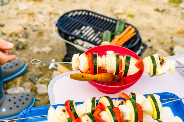 Assorted delicious vegetable skewers on bowl with spice marinade ready to be grilled on barbecue grill. Barbeque dinner outdoor.