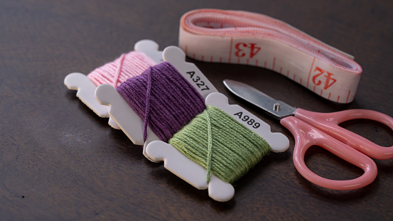 Colorful Crafting: Bobbins of Green, Purple, and Pink Threads on Table