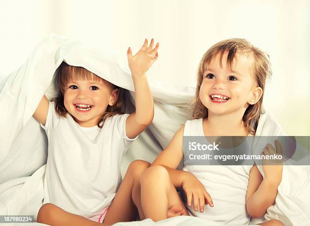 Happy Little Girls Twins Sister In Bed Under The Blanket Stock Photo - Download Image Now