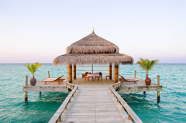 Private Dining on the Water Romantic private dining area on a wooden platform connected to the island with a walkway. pavilion photos stock pictures, royalty-free photos & images