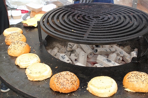 Cooking burger buns with sesame and poppy seeds lightly toasted on grill outdoor on open kitchen international food festival event. Street food cafe. Picnic on backyard of cabin. Hamburger buns toast