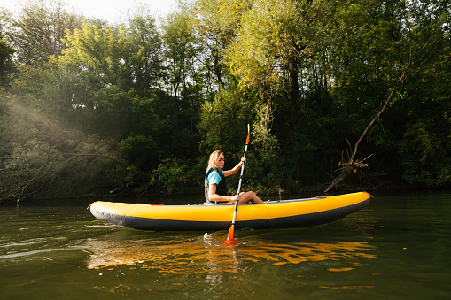 Photo of a young woman kayaking on the river.