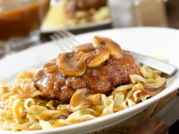 Salisbury Steak Salisbury Steak Topped with Sauteed Mushrooms and Onions, Pasta and Corn on the side and topped with Gravy. - Photographed on Hasselblad H3D2-39mb Camera salisbury steak stock pictures, royalty-free photos & images