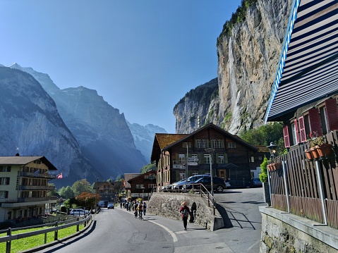 People walking on the street and in the background the Staubbach Falls on a beautiful day in Lauterbrunnen, Switzerland - September 27, 2023