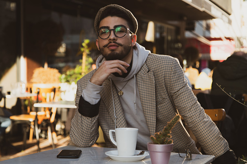 Vintage photo of handsome hipster man drinking coffee outdoors in the city