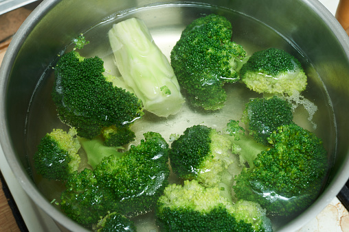 Vegetable in traditional market in Taiwan. Fresh organic green broccoli boiling in water in a stainless pot. Broccoli crucifer raw vegetable closeup shoot. This vegetable is good for healthy salad ingredient. Raw cauliflower.