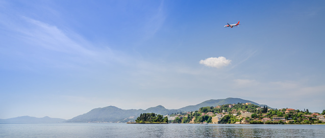 The passenger plane takes off from Corfu Airport in Greek Island of Kerkyra (Corfu) in a backdrop of mountainous terrain. Corfu Airport is great place for plane spotting.