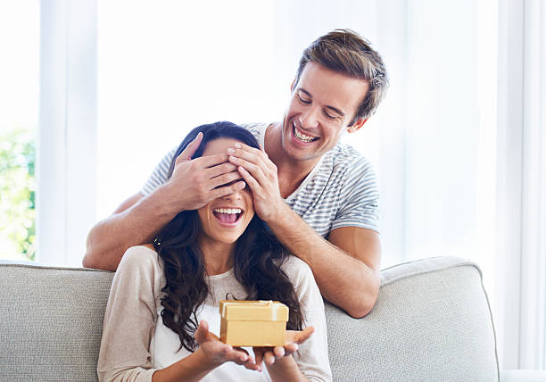 I can't wait to see what it is! A young boyfriend covering his girlfriend's eyes as he gives her a present gift for girlfriend stock pictures, royalty-free photos & images