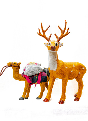 Reins carries a glitter bag on a tissue saddle and a cute reindeer with horns looking at camera. Side view studio shot isolated in white background with copy space