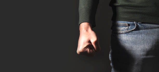 istock angry man fist on black wall background 1879996483