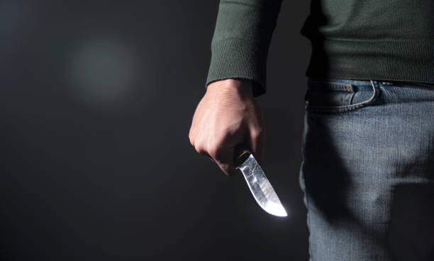 istock man holding a knife on a black background 1879996487