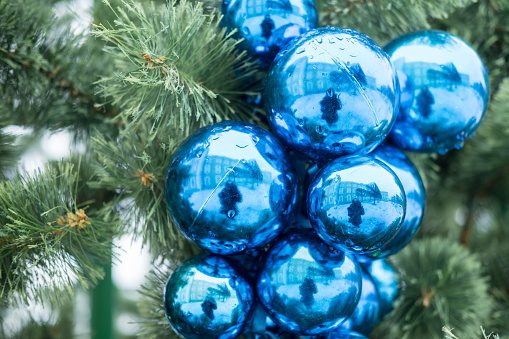 Blurred reflection of woman holding a camera in Christmas ball on Christmas tree.