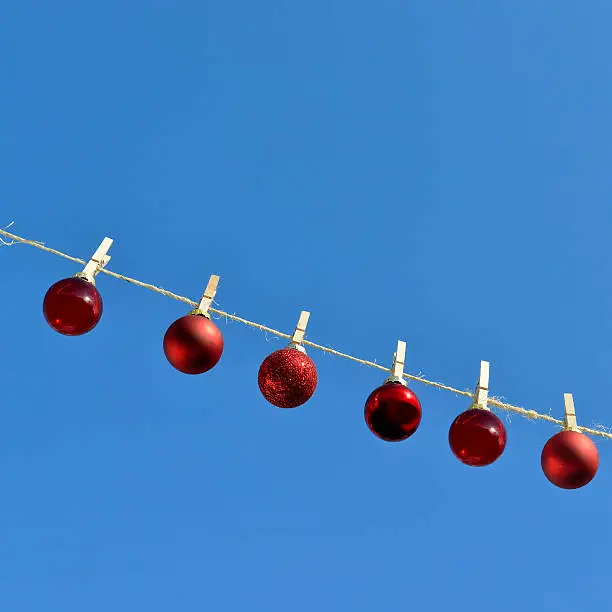Small Christmas baubles hanging on a clothesline.