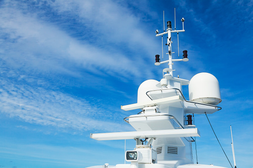 The mast of a large yacht with navigation equipment bottom view. Radar, signal lights, satellite dishes and equipment.