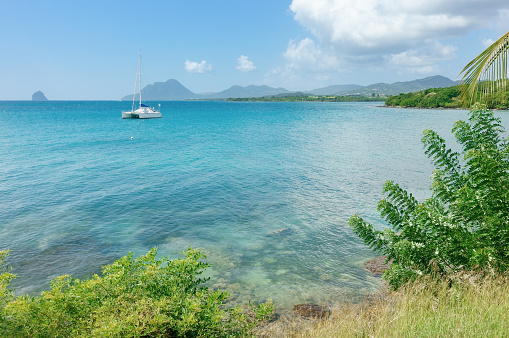 Catamaran moored a in tropical bay of Martinique, with Le Diamant and Le Morne Larcher mountain in background (Anse Mabouya, Sainte Luce, Martinique)