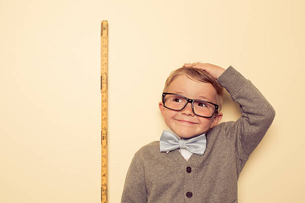 Big A young boy is looking forward to growing and getting bigger. Big things with becoming big. boy height measure stock pictures, royalty-free photos & images