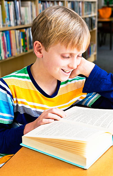 istock Smiling schoolboy in library just loves reading! 188011465