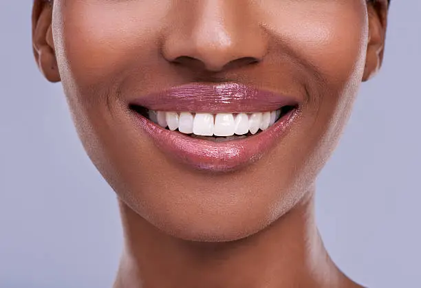 Cropped shot of a young woman's mouth against a purple background