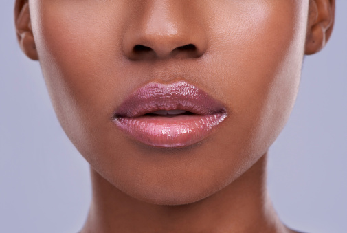 Cropped shot of a young woman's mouth against a purple background