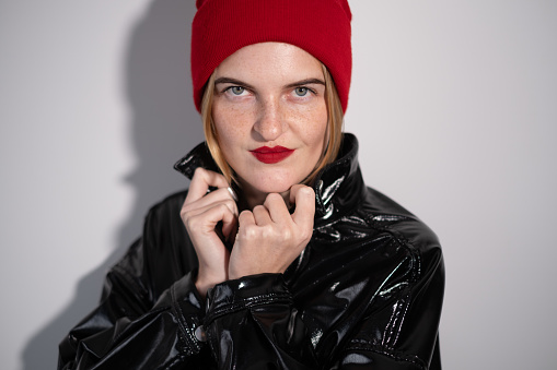 Portrait of a young beautiful woman wearing a shiny leather jacket and a red beret.