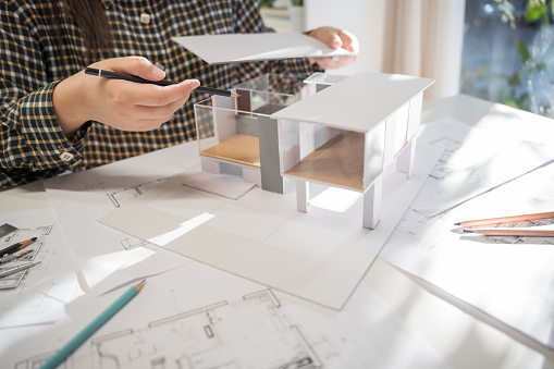 House model on Buleprint construction drawing and drawing equipment stationary Architect analyzing house modelÂ house modern in hand Architect Design Concept