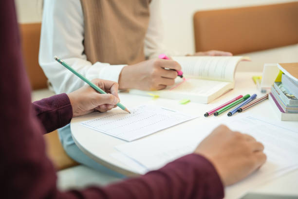 istock Learning with friends Young students campusHigh School Tutor for examining helps school homework together withÂ friend catching up and learning 1880198015