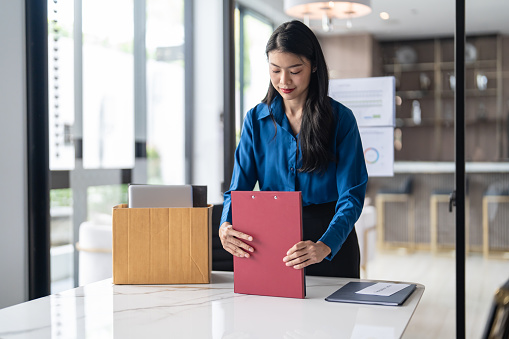 Quit Job asian business woman sending resignation letter and packing Stuff Resign Depress or carrying business cardboard box in office. Change of job or fired from company.
