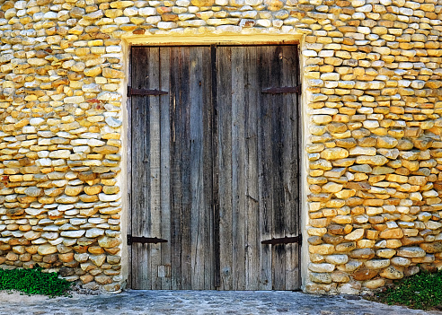 Antique stone building with double doors made of old wood.