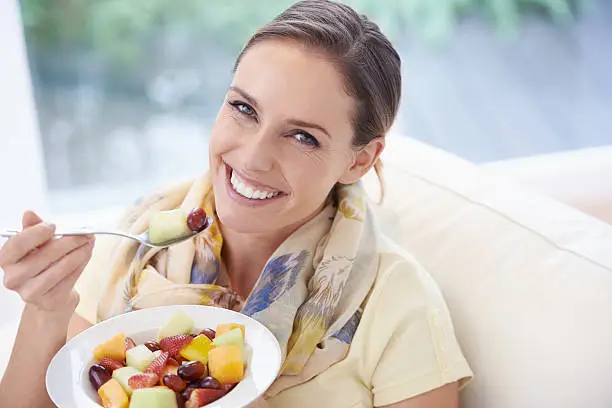 A young woman eating a fruit salad at home