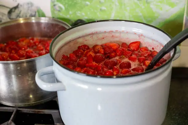 Photo of Juicy sweet strawberry jam is cooked in pans. Preparations for the winter