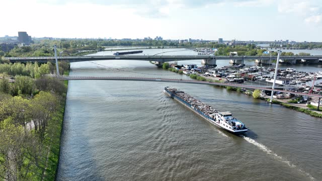 Inland shipping logistics transportation of goods over water way infrastructure in the Netherlands Amsterdam Rijnkanaal. Barge sailing shipment of freight aerial drone view.