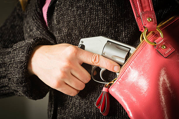 Woman Carrying Handgun A close-up of a woman holding a handgun in a purse. concealed carry purses for women stock pictures, royalty-free photos & images