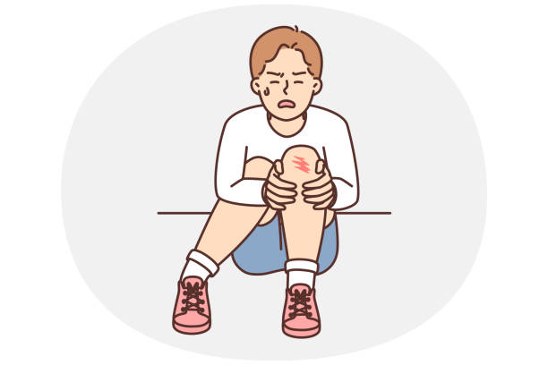 Crying boy sits on ground and holds on to injury on knee after fall during walk Crying teenager boy sits on ground and holds on to injury on knee after fall during walk. Unfortunate child was injured during sports activities or active games with friends knee contusion bruised knee stock illustrations