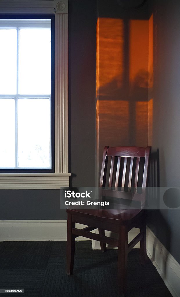 Chair with sunset window glow Orange sunset glow above a solitary chair. Chair Stock Photo