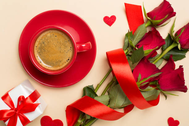 istock Red cup of coffee with roses on color background, top view 1880482505