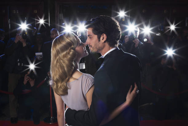 paparazzi fotografare celebrità coppia baciare al tappeto rosso - evening gown flash foto e immagini stock