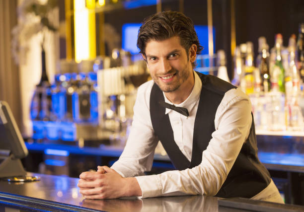 Handsome barman holding a pint of beer in a pub