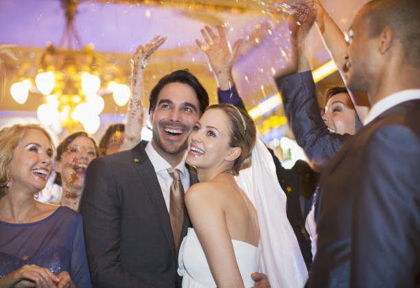 istock Friends throwing confetti over bride and groom at wedding reception 188051805
