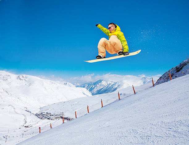 istock Cute snowboarder man jumping on ski resort 188052199