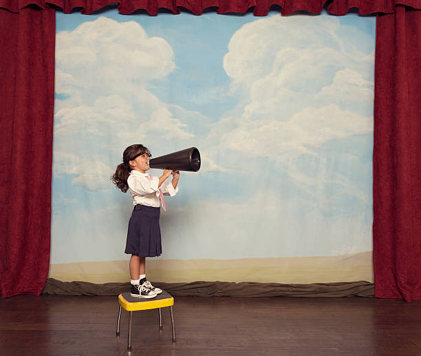 Young Girl Dressed as Businesswoman Yells Through Megaphone A young girl makes sure to have her voice heard for her business.  resourceful stock pictures, royalty-free photos & images