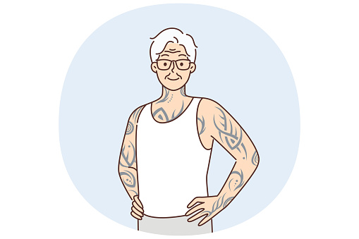 Optimistic elderly man with tattoos on arms and body stands with hands on belt proud good health in old age. Gray-haired elderly human with tattoos stuffed in youth looks at screen posing in t-shirt