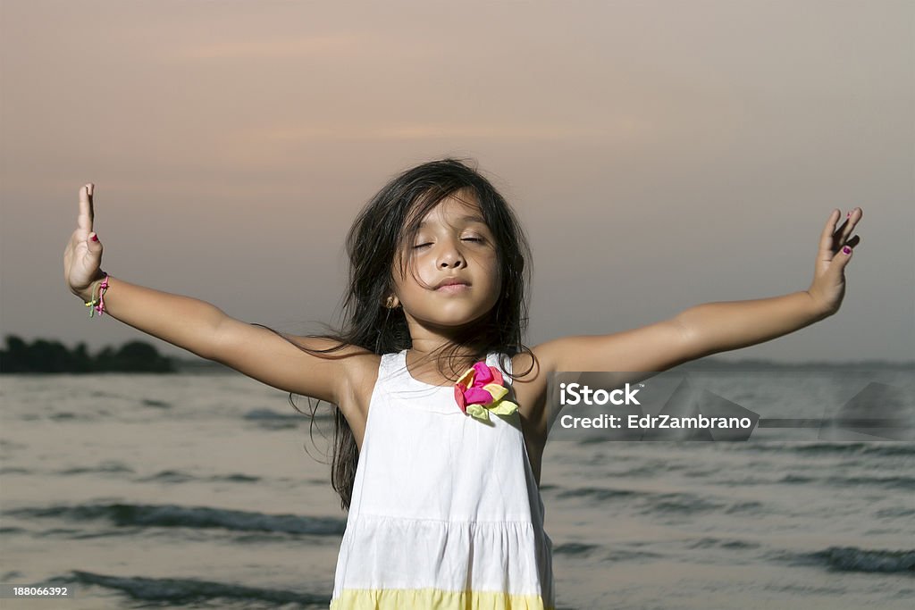Long black haired girl with her arms outstretched Long black haired girl with her arms outstretched and eyes closed in meditation position Beach Stock Photo