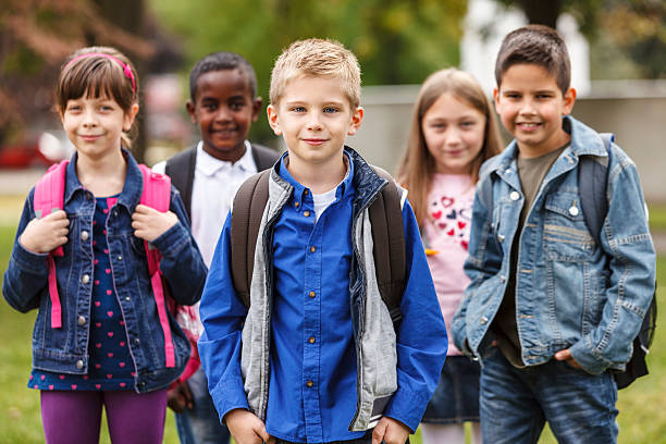 istock School children standing outdoors with bookbags 188070321