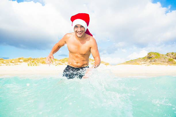 istock man in santa hat having fun by the sea 188070457
