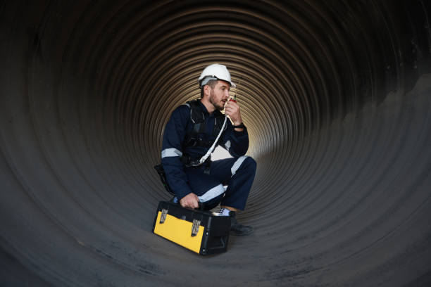 istock Mechanical engineer with coverall safety suit and tool box work in a huge tube, infrastructure construction 1880710705